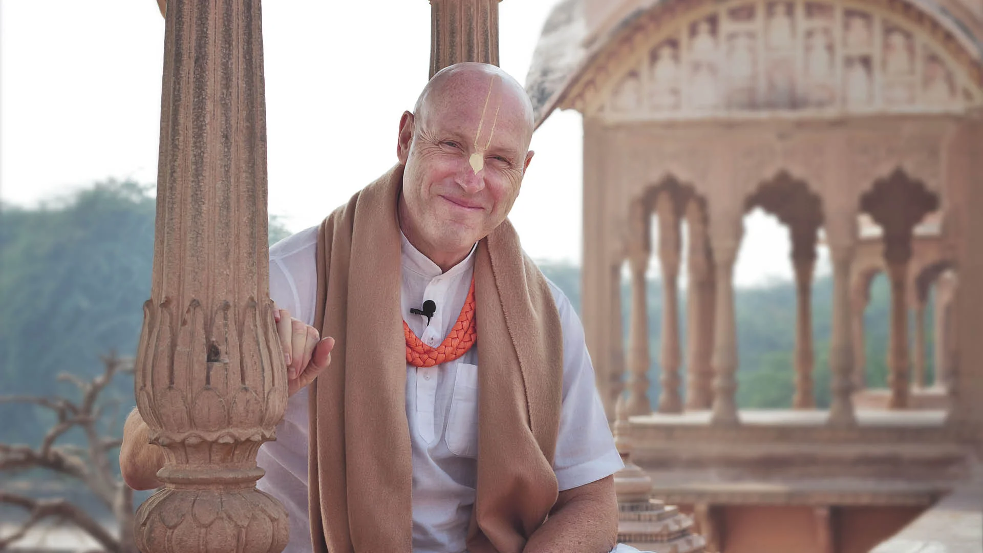 His Grace Vaiśeṣika Dāsa, smiling in a white kurta with tilak at a temple